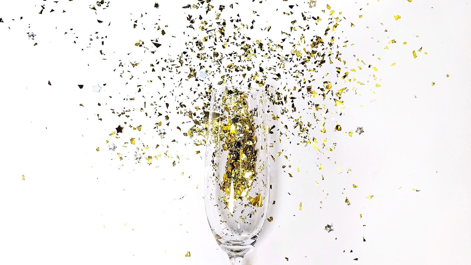 a champagne glass with glitter being blown from it.