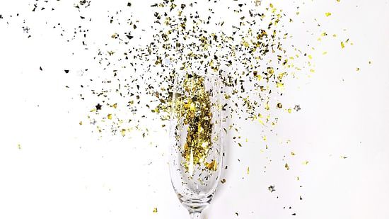 a campagne glass with glitter being blown from it