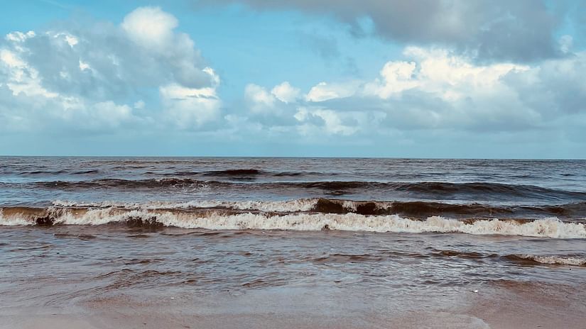 A view of waves moving about on a beach on a cloudy day. 