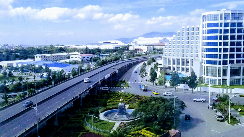 Aerial view of Addis Ababa, featuring vehicles on highways passing by large buildings under a blue sky