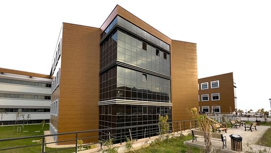 An image of a building surrounded by lawns where benches are placed