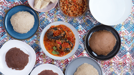 Traditional table spread featuring Fufu dough mounds paired with various local stews and side dishes.