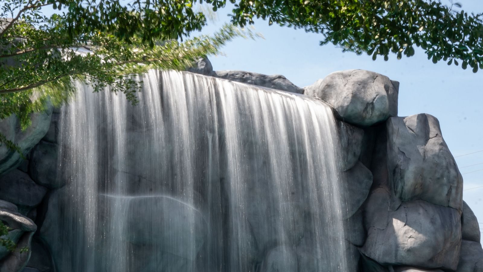 A wide-angle view showcasing a waterfall-like structure with a pool in the foreground, offering one of the best fun things to do in Coimbatore for the whole family.