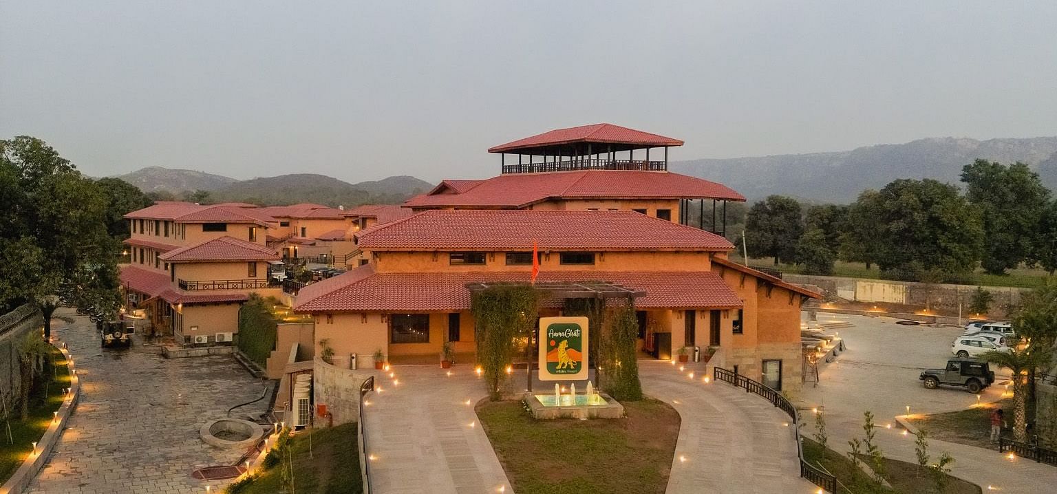 An expansive view of the resort courtyard with illuminated pathways from above, at Aamaghati Wildlife Resort.