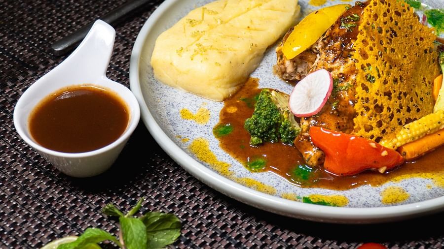 A plate with fish, a side of sauce, and a garnish.