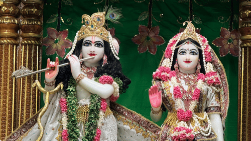 Ornate, beautifully dressed statues of Hindu deities Radha and Krishna holding a flute.