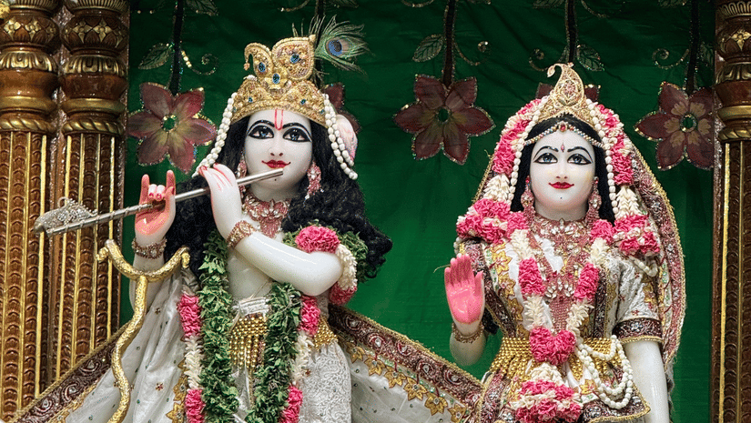 Ornate, beautifully dressed statues of Hindu deities Radha and Krishna holding a flute.
