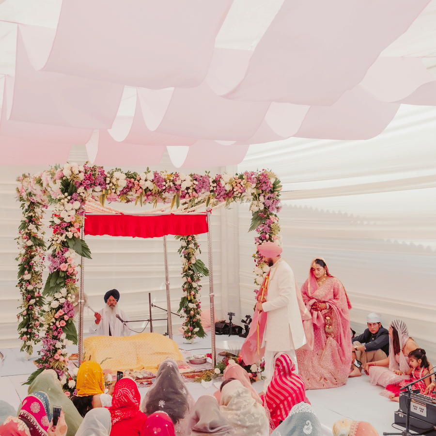 A vertical view of a wedding mandap decorated with leaves and flowers beneath draped white fabric panels at an outdoor ceremony at Umaid Palace.