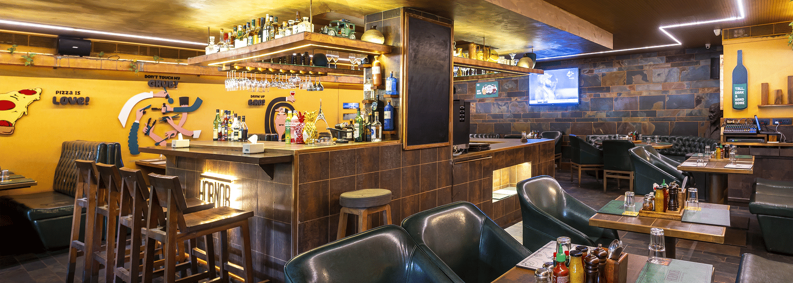 A restaurant interior with high tables, chairs and wall murals in a rustic wooden setting at Infiniti Hotel, Indore.