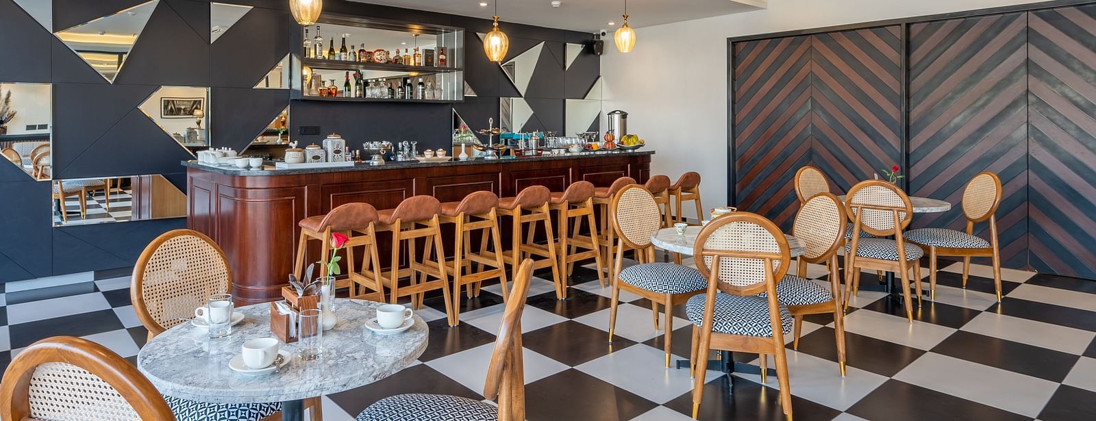 Shot of a bar at Vishranti Hotel Dehradun with chairs table and checkered floors. 