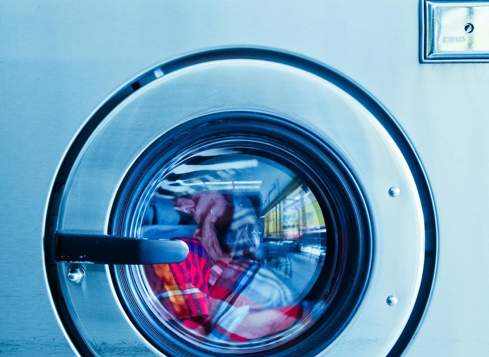 A close-up of a front-loading washing machine with clothes visible inside the drum.