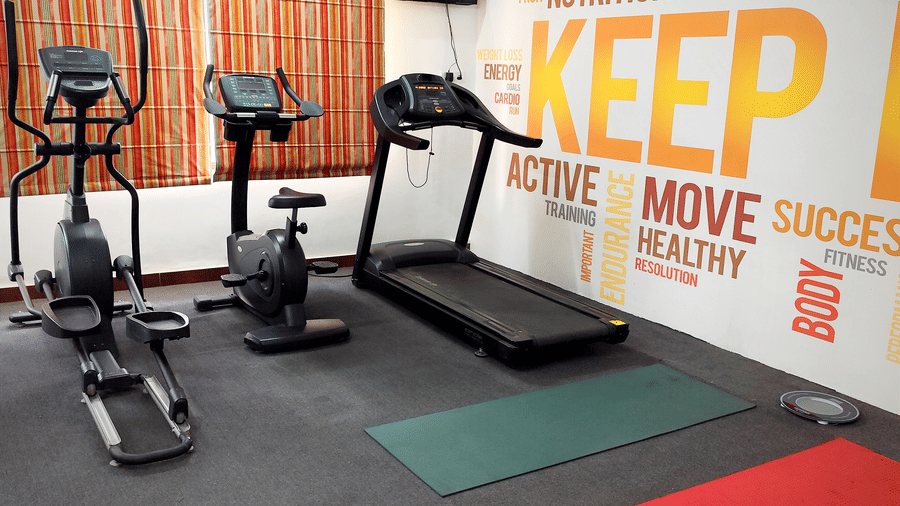An indoor gym featuring an elliptical machine, a stationary bike, a treadmill, and two yoga mats on the floor | HHI Varanasi