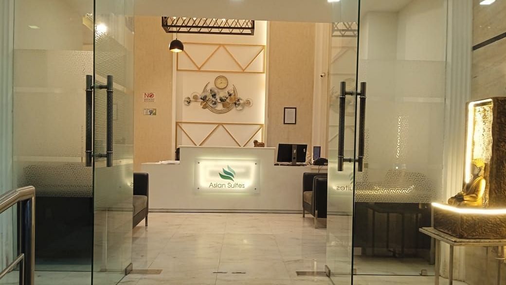 A modern entrance with glass doors and decorative wall panels leads into a brightly lit interior space - Asian Suites Cyber Park, Gurgaon