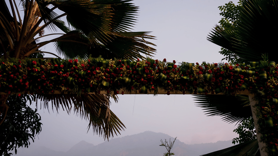 Floral archway adorned with vibrant flowers and greenery, creating a romantic entrance with palm trees in the background at Black Thunder, Coimbatore