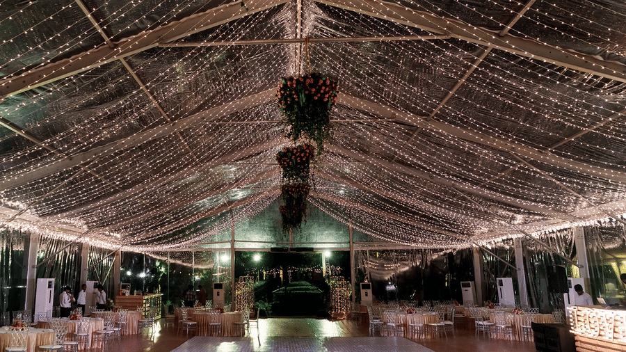 Elegantly decorated indoor event venue with draped lighting, floral chandeliers, and a stage in the center, creating a festive atmosphere at Black Thunder, Coimbatore