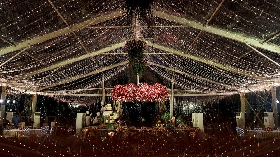Spacious event hall with ceiling lights and hanging floral arrangements, featuring a central aisle leading to a stage at Black Thunder, Coimbatore
