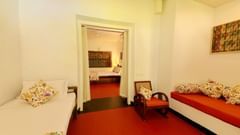 The Tower House - inner view of a beautiful room with two separate single beds on either side of the room and a pathway that leads to a second bedroom that features another queen size bed