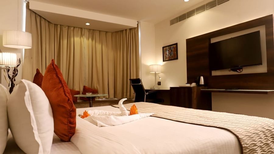 a side shot of the deluxe room with a double bed and a tv opposite to it inside deluxe rooms at 5 flowers ananta elite, kota