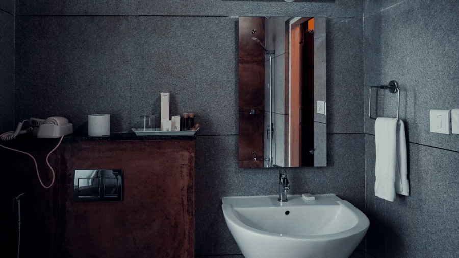 A modern bathroom is equipped with a sink, toilet, and mirror, providing essential facilities.- Abad Brookside Lakkidi, Wayanad