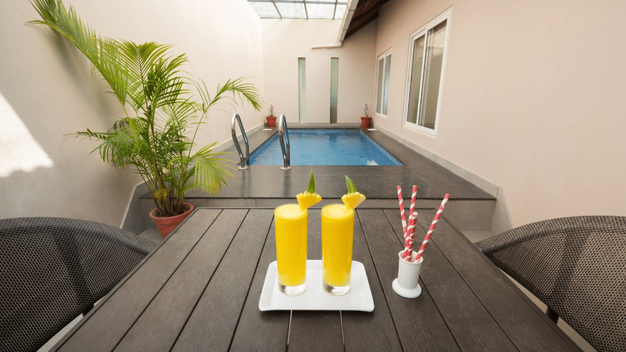 An outdoor table is set with drinks next to a pool, offering a relaxing poolside experience.- Abad Brookside Lakkidi, Wayanad