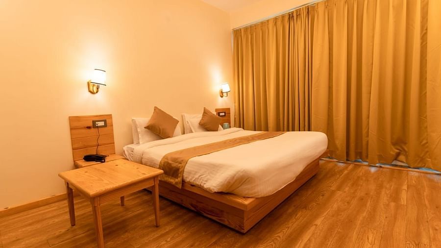 A bedroom with two beds, a desk, and a view of the outside - Clarks Exotica Resort, Near Mukhteshwar.