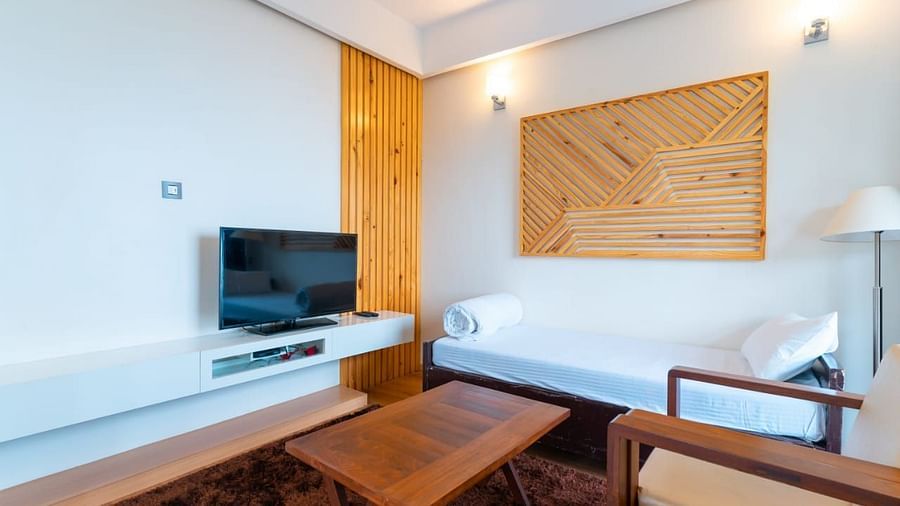 A living room area with a couch, a television, and warm lighting, interior setting - Clarks Exotica Resort, Near Mukhteshwar.