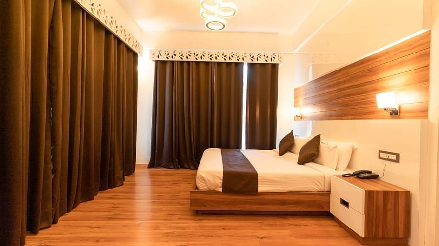 A bedroom with a white bed, a rug, and warm lighting, interior setting - Clarks Exotica Resort, Near Mukhteshwar.