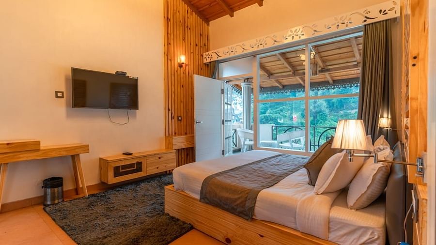 A bedroom with a bed, a rug, and warm lighting, interior setting, with a view to the outside - Clarks Exotica Resort, Near Mukhteshwar.