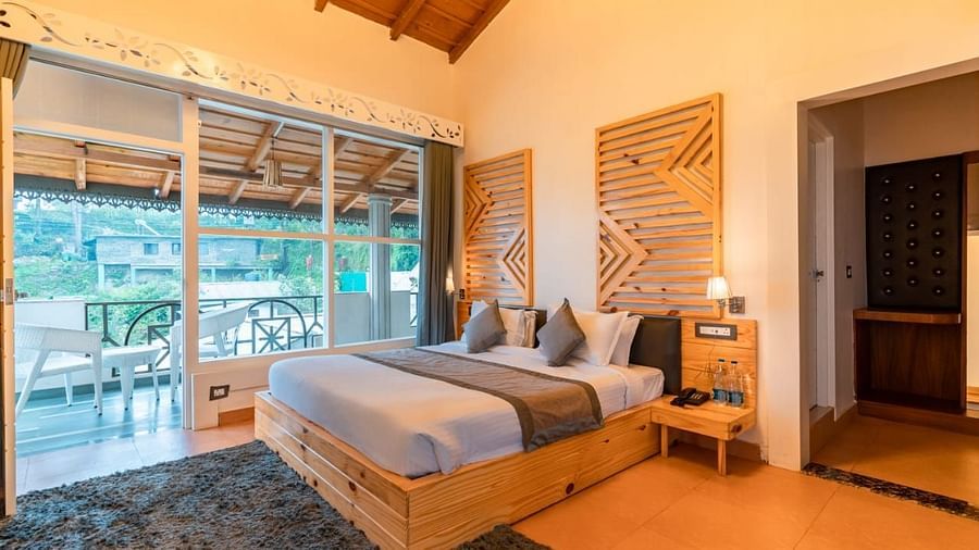 A bedroom with a bed, a rug, and warm lighting, interior setting, with a view to the outside - Clarks Exotica Resort, Near Mukhteshwar.