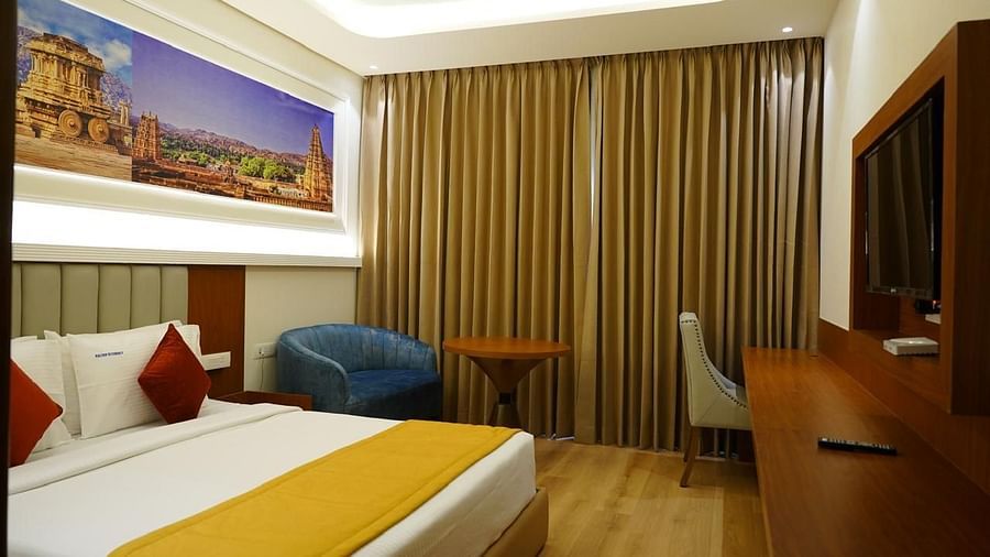 Elegant room with full-length curtains, artwork, and queen bed at Kalyan Residency Hotel, Tirupati.