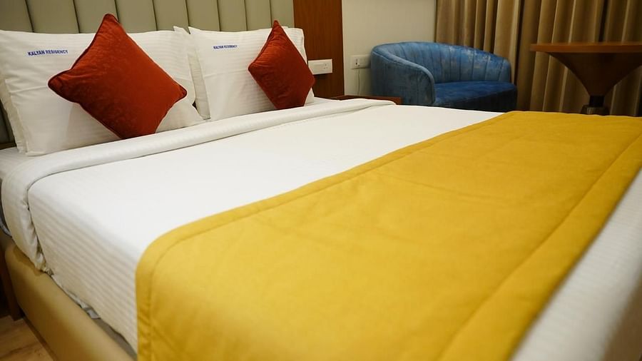 Close-up of a  bed with red cushions and yellow runner at Kalyan Residency Hotel, Tirupati – inviting and well-styled.