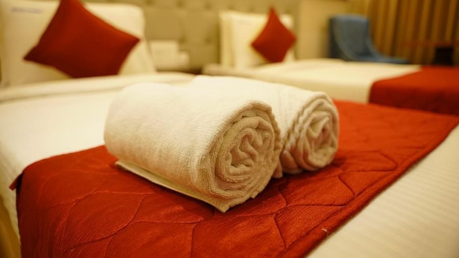 Fresh towels placed on red bed runners in a twin room at Kalyan Residency Hotel, Tirupati – attention to detail for guest comfort.