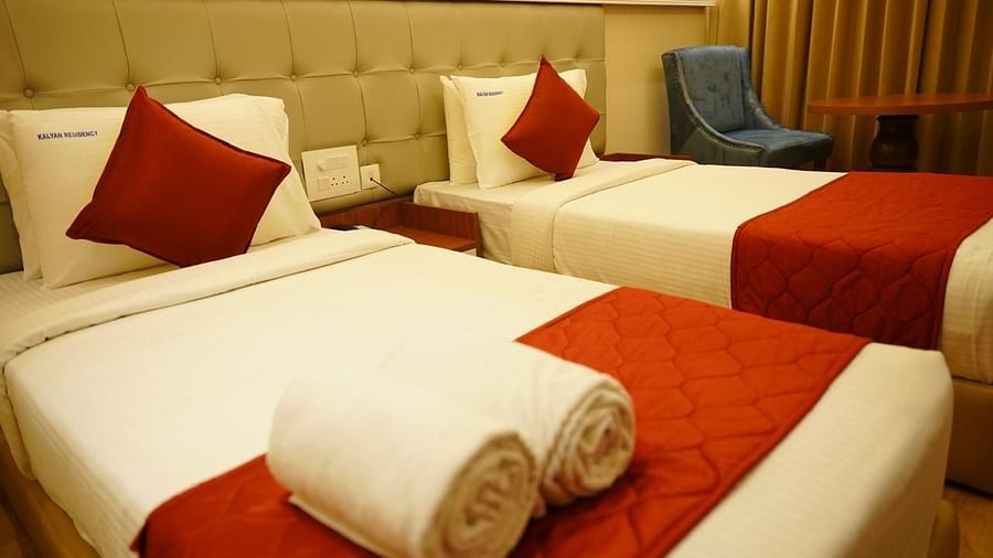 Elegant twin bedroom with red accents and cosy lighting at Kalyan Residency Hotel, Tirupati – warm and inviting.