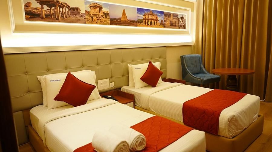 Neat twin bedroom with headboard art and warm lighting at Kalyan Residency Hotel, Tirupati – suited for leisure or business stays.