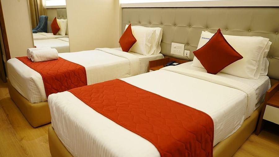 Bright twin room with plush bedding and red accents at Kalyan Residency Hotel, Tirupati – ideal for a relaxing stay.
