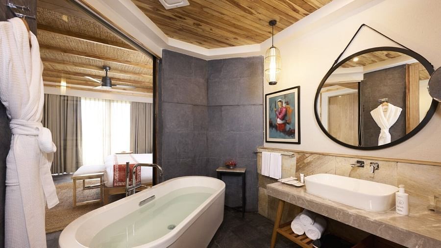 Modern bathroom with a freestanding bathtub, circular mirror, and wood accents - Royal Tulip, Chitwan