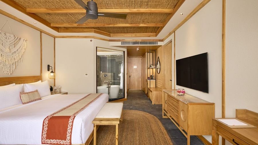 Bright room featuring double bed, ceiling fan, TV, and an attached washroom - Royal Tulip, Chitwan