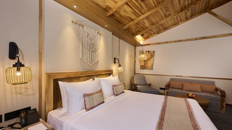 Warmly lit room with double bed, fan, bedside lamps, and wall-mounted lighting - Royal Tulip, Chitwan