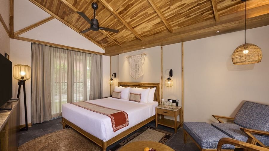 Hotel bedroom with seating area, double bed, fan, and hanging pendant lights. - Royal Tulip, Chitwan