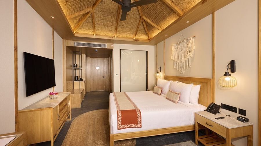 Elegant Chitwan room featuring double bed, a night stand, ceiling fan, TV, and wood-detailed decor. - Royal Tulip, Chitwan