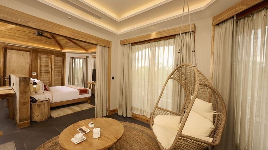 A Chitwan Villa with double bed, hanging chair, fan, round table, and balcony access - Royal Tulip, Chitwan