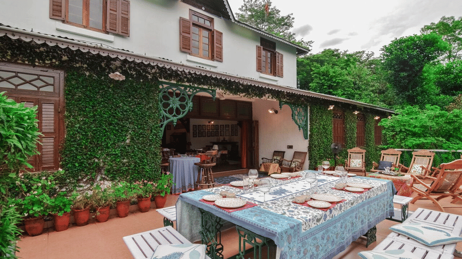 Outdoor dining setup at Shaheen Bagh - A Luxury Boutique Resort & Spa in Dehradun, featuring chairs and benches arranged around a table with cutlery placed on the table mat