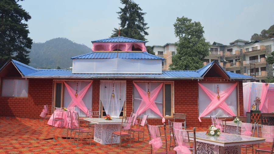 A colorfully decorated setting with seats, chairs and tables, and a background of the trees and hills