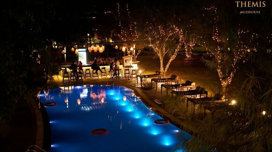 Well-lit swimming pool at night at inflated trampoline surrounded by trees at Themis Mudhouse - A Nature's Retreat Resort & Wellness