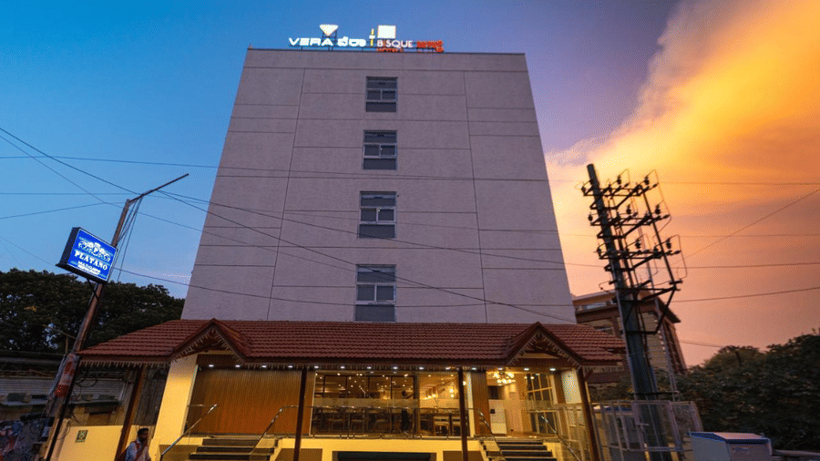 The facade of VITS Select, Bengaluru as seen from the front, featuring stairs leading up to the hotel with a vibrant sky in the background.