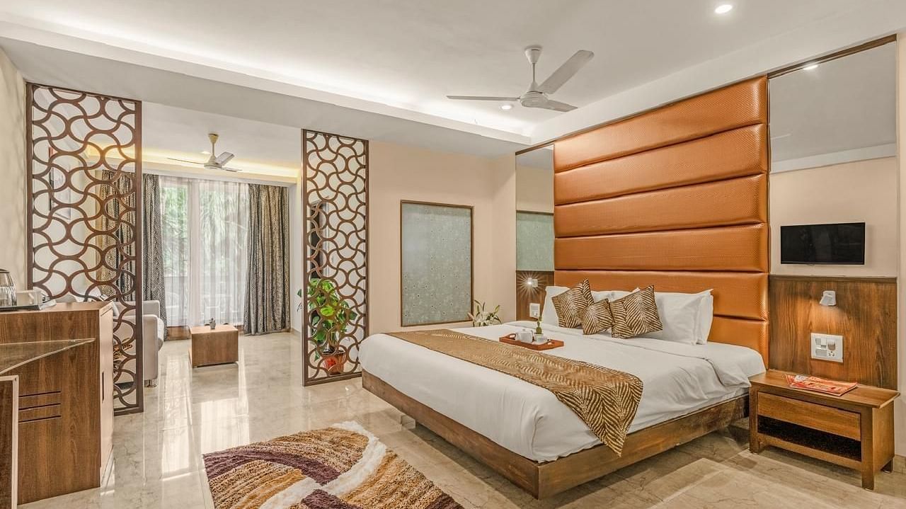 Image of Grand Room with a bed and a wooden side table at Calux Joia Do Mar Resort, Goa.