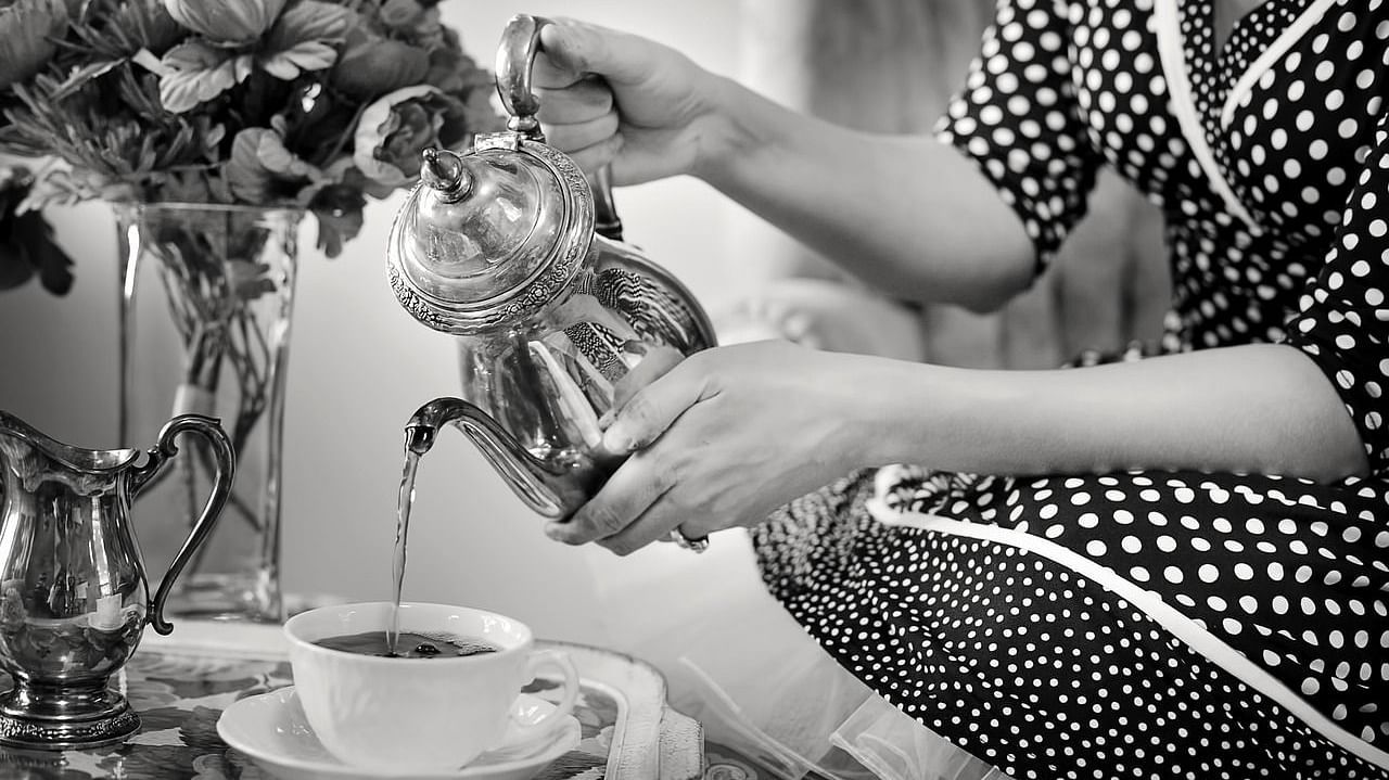 A women pouring tea into a cup.