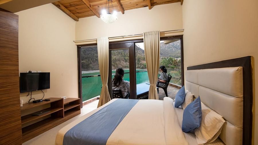 Double bed facing a flat-screen TV and glass doors opening to a balcony 