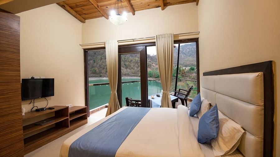 Double bed facing a flat-screen TV and glass doors opening to a balcony 