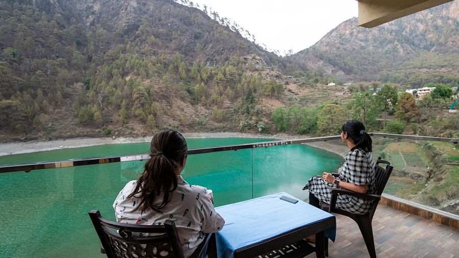 Two people seated at a table on a balcony with a scenic lake and mountain view.